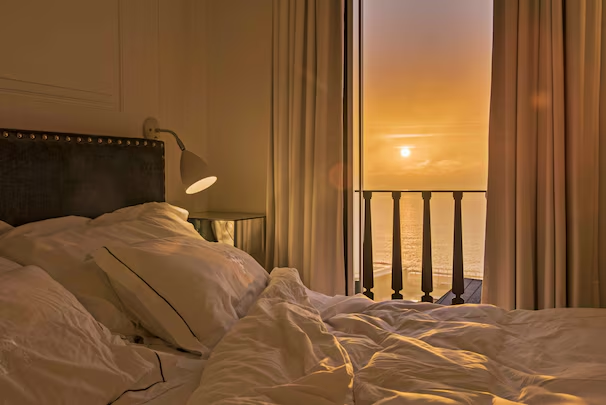 Santiago de Alfama — bedroom with sunset view over Lisbon rooftops