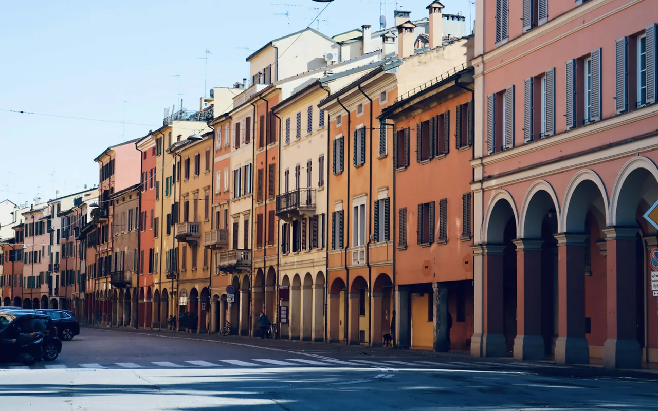 Warm terracotta facades and porticoes along a Bologna street