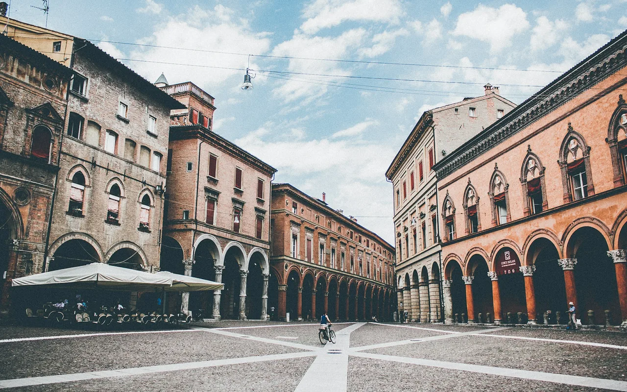 Sunlit street and historic arcades near Bologna's food market lanes